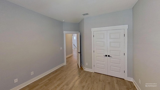 unfurnished bedroom with light wood-style floors, baseboards, and a closet