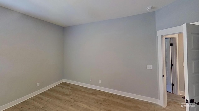 unfurnished room featuring light wood-type flooring, baseboards, and a smoke detector