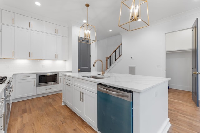 kitchen featuring stainless steel dishwasher, built in microwave, a kitchen island with sink, white cabinetry, and hanging light fixtures