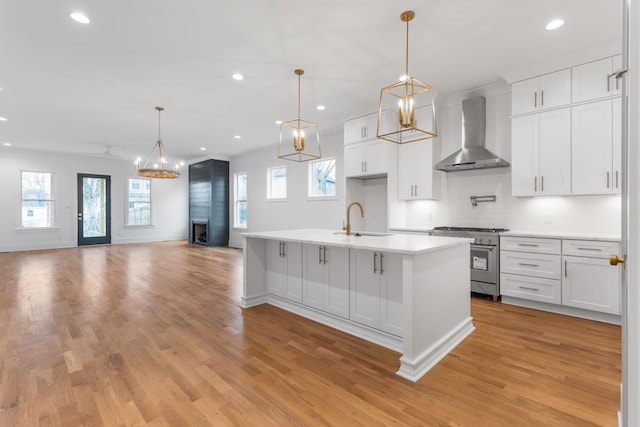 kitchen featuring wall chimney exhaust hood, white cabinetry, high end stove, and sink