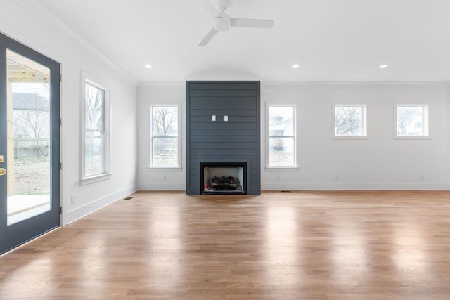 unfurnished living room featuring a fireplace, light hardwood / wood-style floors, a wealth of natural light, and ornamental molding