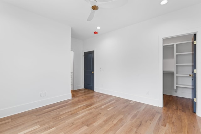 unfurnished bedroom featuring a walk in closet, ceiling fan, a closet, and light wood-type flooring