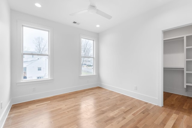 unfurnished bedroom featuring ceiling fan, a spacious closet, light hardwood / wood-style flooring, and a closet