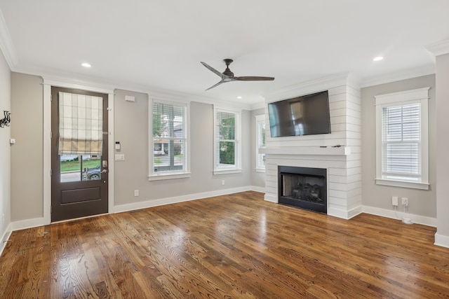 unfurnished living room with ornamental molding, wood-type flooring, ceiling fan, and a large fireplace