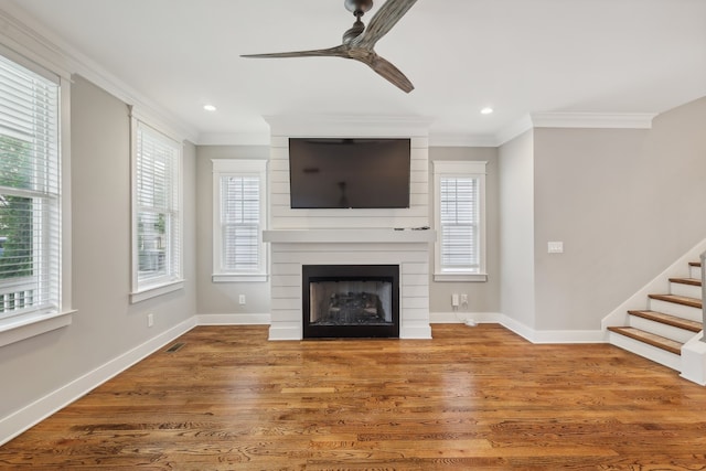 unfurnished living room featuring ceiling fan, a fireplace, hardwood / wood-style floors, and a wealth of natural light