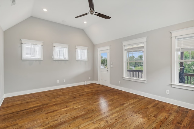 empty room with ceiling fan, vaulted ceiling, hardwood / wood-style floors, and a wealth of natural light