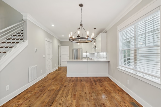 kitchen featuring pendant lighting, white cabinets, kitchen peninsula, stainless steel refrigerator, and dark hardwood / wood-style flooring