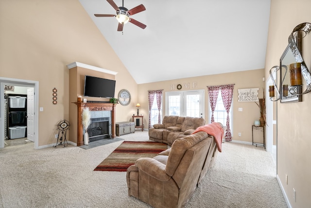 living room featuring high vaulted ceiling, a tiled fireplace, ceiling fan, and light carpet