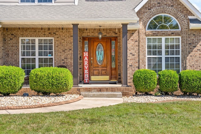 entrance to property featuring a lawn and a porch