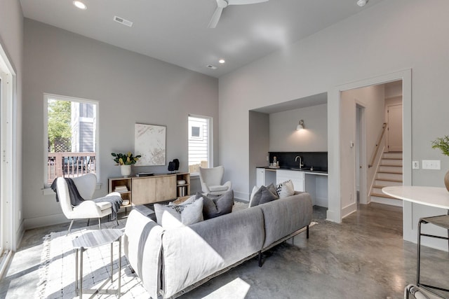 living room featuring a high ceiling, ceiling fan, and sink