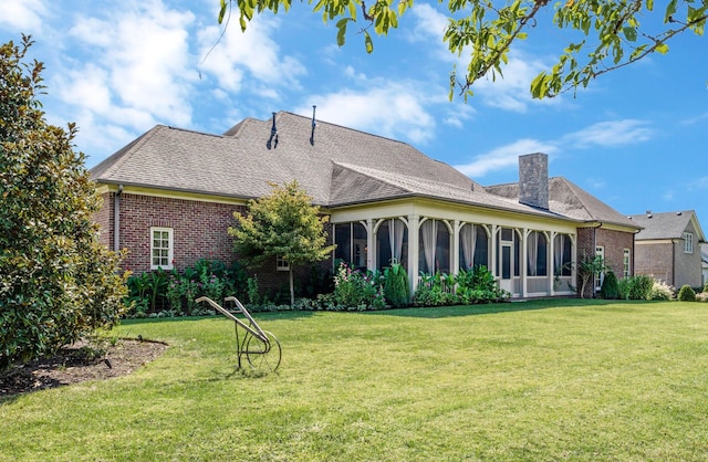 rear view of house with a sunroom and a lawn