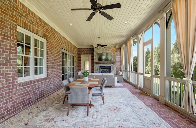 sunroom featuring wood ceiling, an outdoor stone fireplace, and ceiling fan