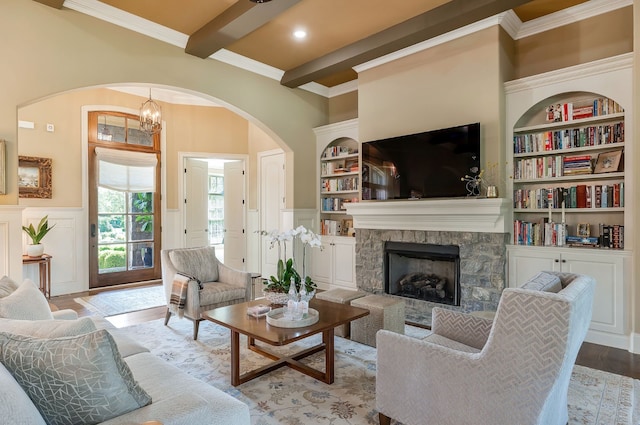 living room with light wood-type flooring, built in shelves, beam ceiling, and a fireplace