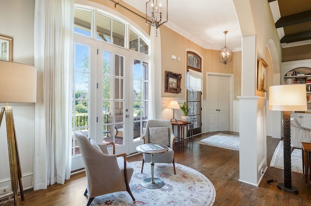 sitting room with french doors, an inviting chandelier, dark wood-type flooring, and crown molding