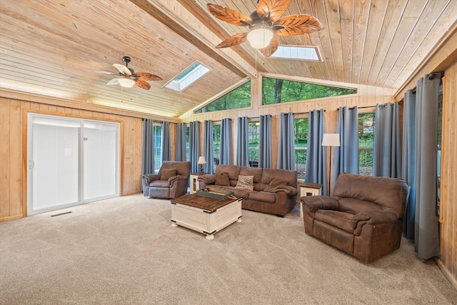 carpeted living room featuring wood ceiling, vaulted ceiling with skylight, wood walls, and ceiling fan