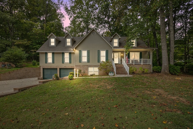 cape cod house with a yard, a porch, and a garage