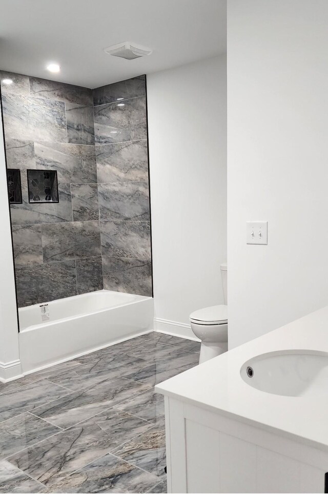 full bathroom featuring tiled shower / bath, vanity, and toilet