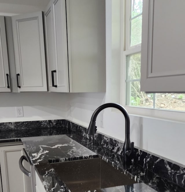 interior space featuring dark stone counters, plenty of natural light, and sink