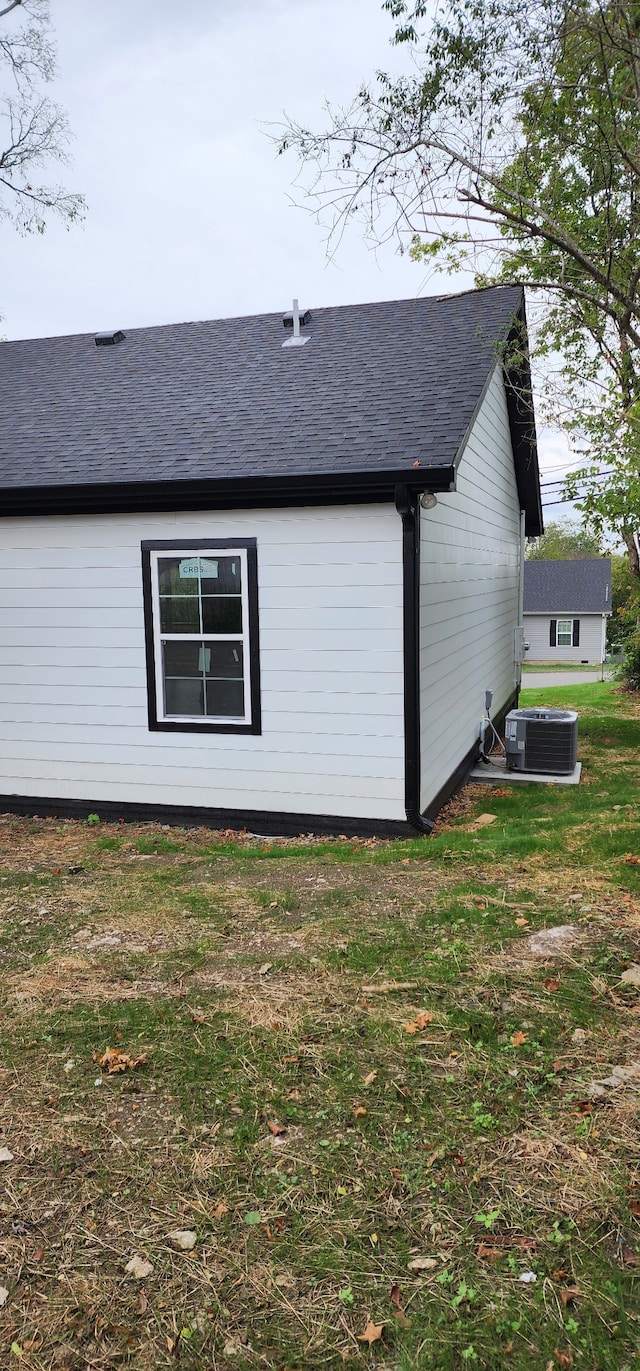 view of side of property with a lawn and central AC