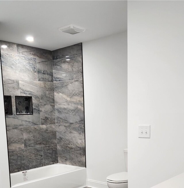 bathroom with tiled shower / bath combo and toilet