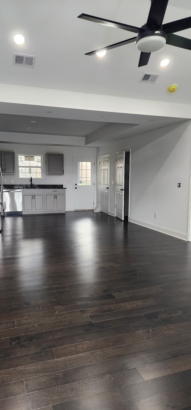 unfurnished living room featuring dark hardwood / wood-style flooring, ceiling fan, sink, and a wealth of natural light