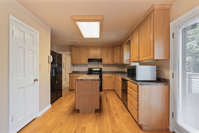 kitchen featuring black appliances, light brown cabinets, light wood-type flooring, and a center island