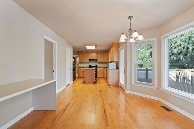 kitchen with black range with electric stovetop, light wood-type flooring, an inviting chandelier, decorative light fixtures, and extractor fan