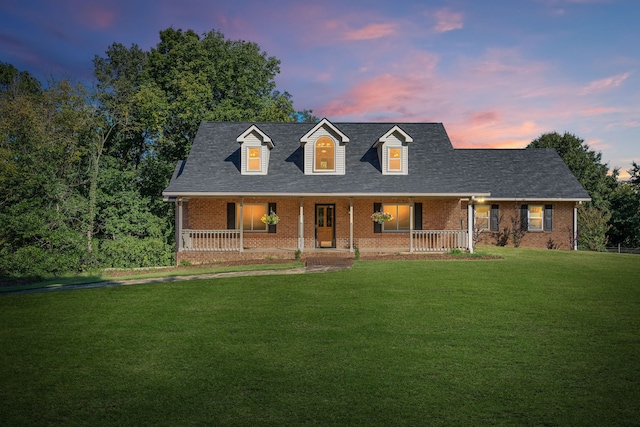 cape cod house with a lawn and covered porch