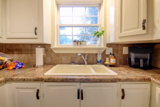 kitchen featuring white cabinets, backsplash, and sink