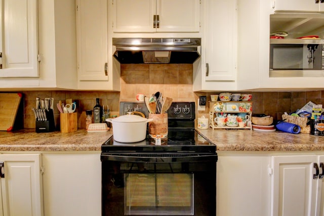 kitchen with white cabinets, backsplash, range hood, and black electric range