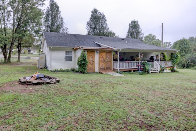 rear view of property featuring a lawn and a fire pit