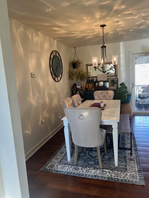 dining space featuring dark hardwood / wood-style floors and an inviting chandelier