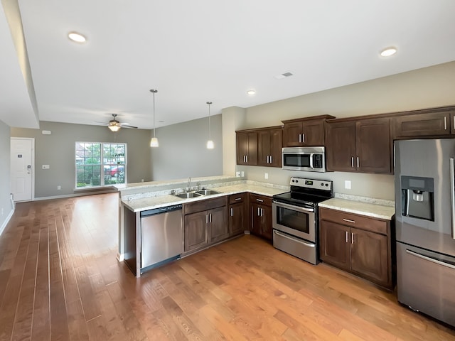 kitchen featuring ceiling fan, pendant lighting, sink, wood-type flooring, and stainless steel appliances