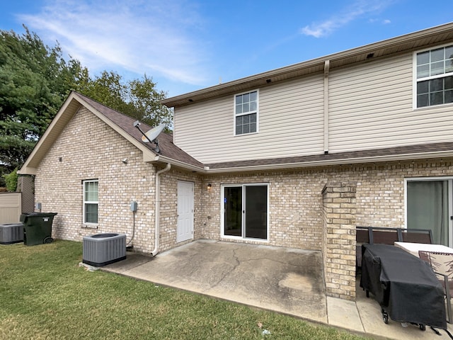 back of property with a patio area, central air condition unit, and a yard