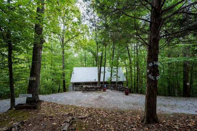 exterior space featuring a forest view, a pole building, and an outbuilding