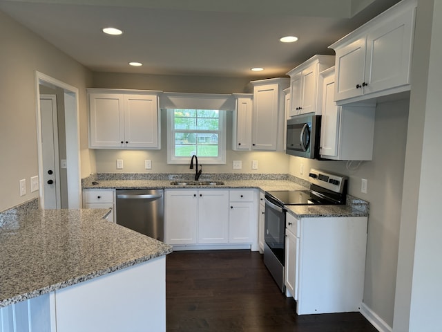 kitchen with sink, light stone counters, dark hardwood / wood-style flooring, stainless steel appliances, and white cabinets