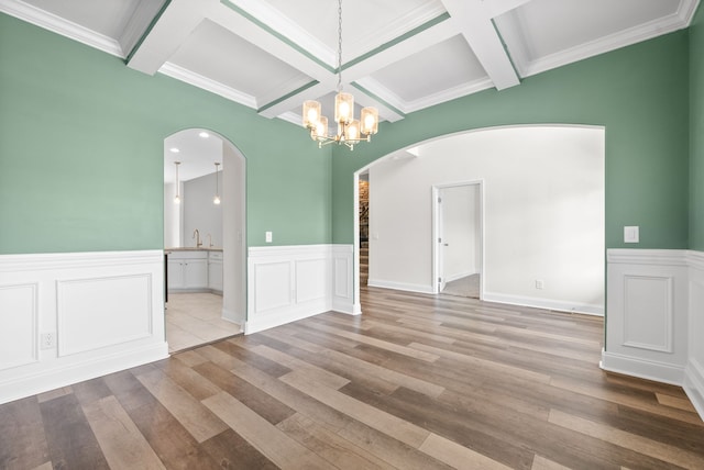 spare room featuring beamed ceiling, sink, a notable chandelier, light hardwood / wood-style flooring, and ornamental molding