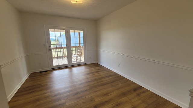 empty room with dark hardwood / wood-style floors and a textured ceiling