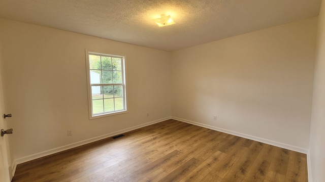 unfurnished room with wood-type flooring and a textured ceiling