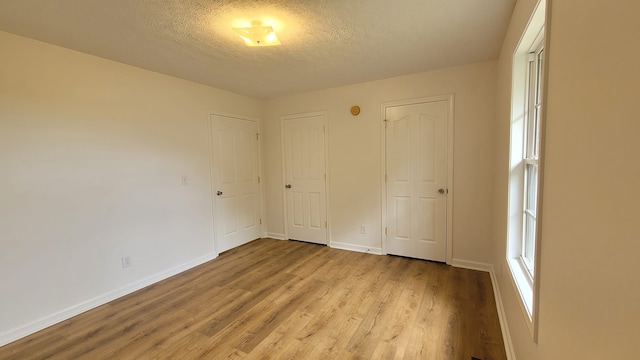 unfurnished bedroom with light hardwood / wood-style floors and a textured ceiling