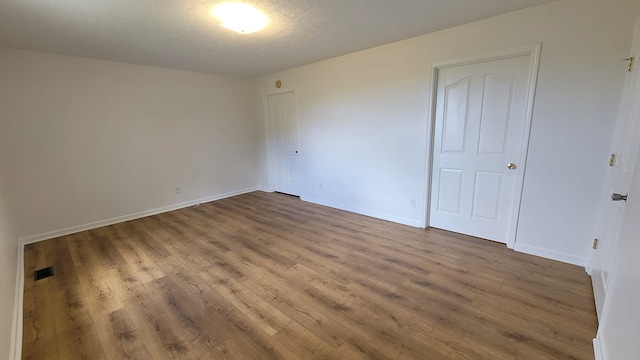 empty room featuring wood-type flooring and a textured ceiling