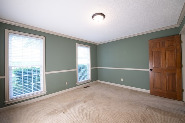 carpeted empty room with a textured ceiling, ornamental molding, and plenty of natural light