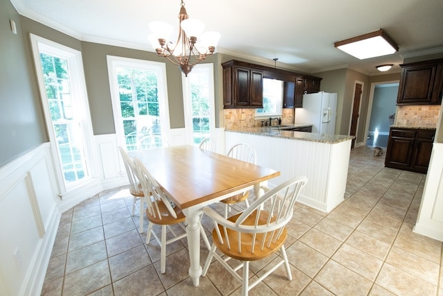 dining space with crown molding, an inviting chandelier, light tile patterned floors, and sink