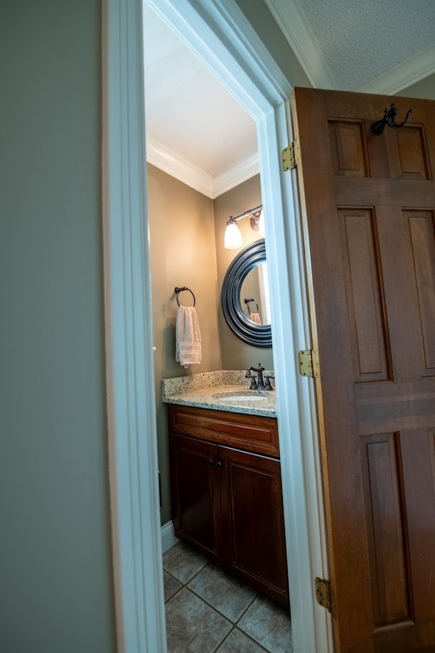 bathroom featuring tile patterned floors, a textured ceiling, vanity, and crown molding