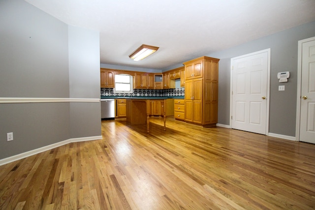 kitchen with a breakfast bar area, light hardwood / wood-style floors, dishwasher, and tasteful backsplash