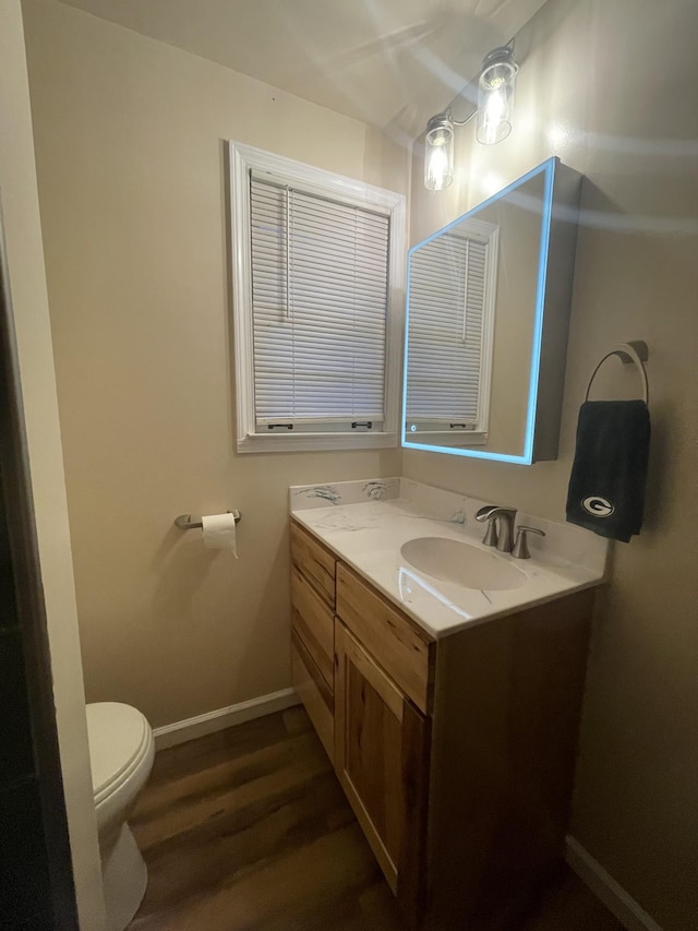 bathroom with hardwood / wood-style floors, vanity, and toilet