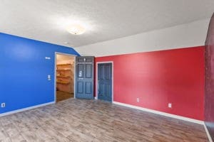 unfurnished room with hardwood / wood-style floors and vaulted ceiling