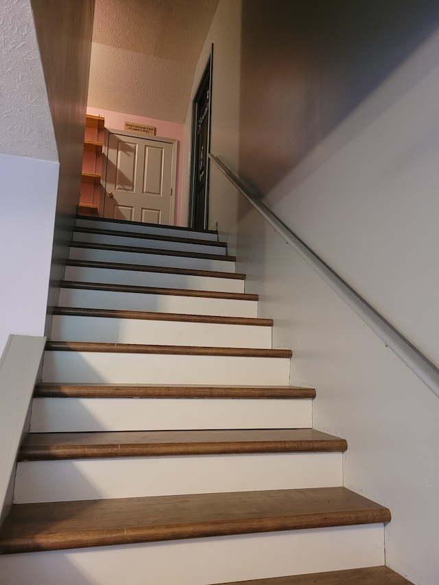 staircase with a textured ceiling