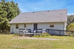 back of property featuring a lawn, a deck, and an outdoor hangout area