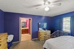 bedroom with ceiling fan, carpet floors, and ensuite bathroom